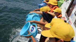 船上からヒラメ稚魚を放流する平塚市立港小学校の児童