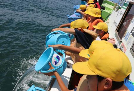 船上からヒラメ稚魚を放流する平塚市立港小学校の児童